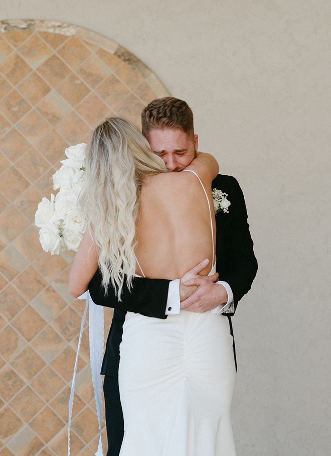 The groom crying as he hugs the bride after the first look. 