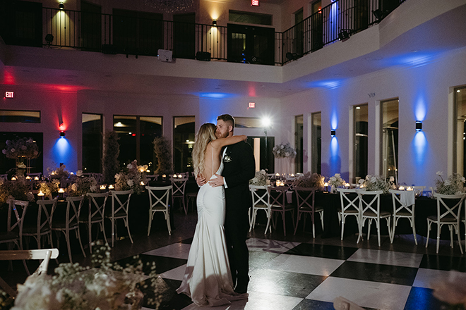 The bride and groom having a private dance on the black-and-white checkered dance floor. 