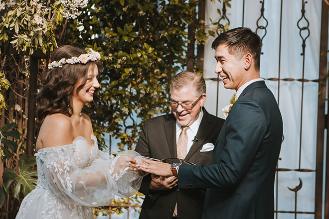 The bride and groom stand at the alter holding hands during their wedding ceremony.