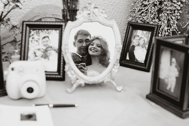 The bride and groom smile into a mirror at their art nouveau wedding at AvantGarden.