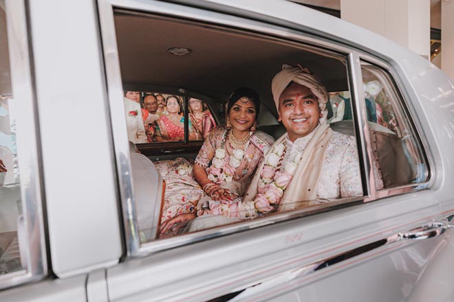 The bride and groom ride off in a vintage luxury car from their wedding venue.