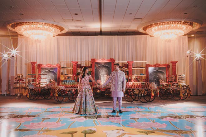 The bride and grooms hold hands on the dance floor at their Sangeet at The Westin Galleria Houston.