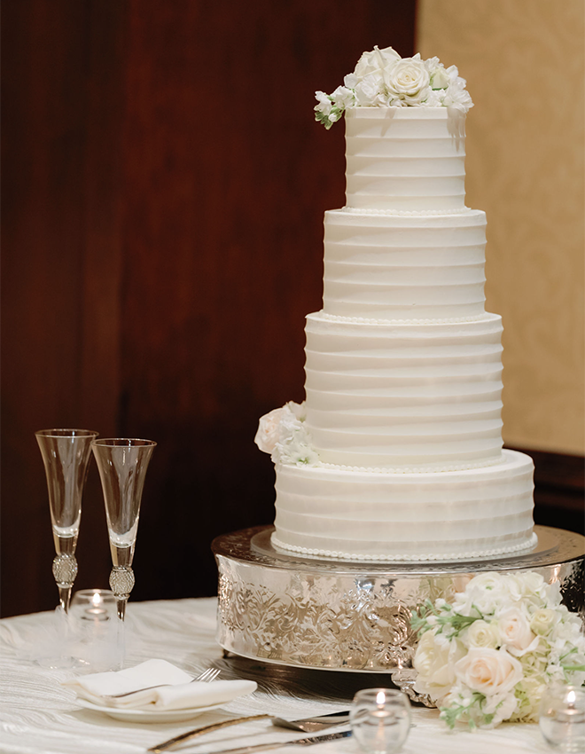 A four white-tier cake with floral garnishes by Susie's Cakes. 