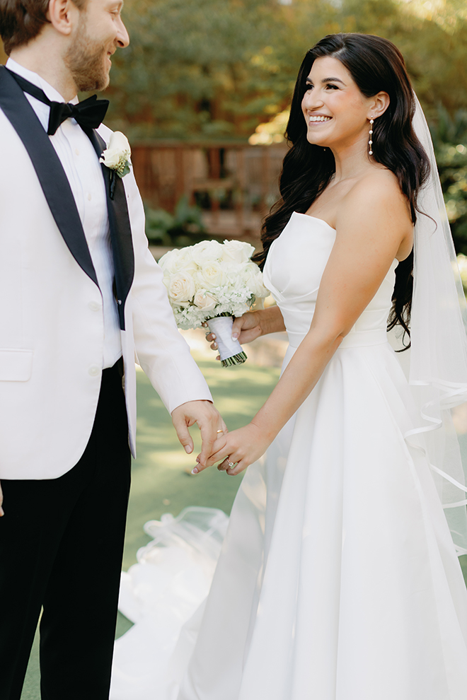 The bride and groom touching hands and smiling at each other at The Houstonian Hotel, Club and Spa. 