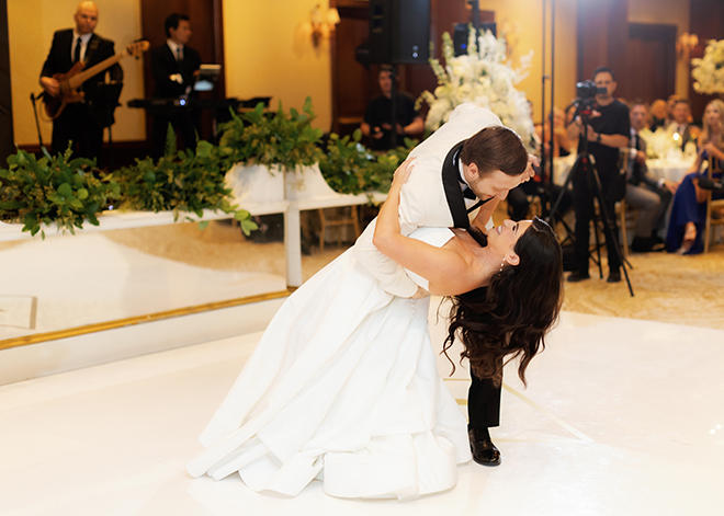 The groom dipping the bride on the white dance floor. 