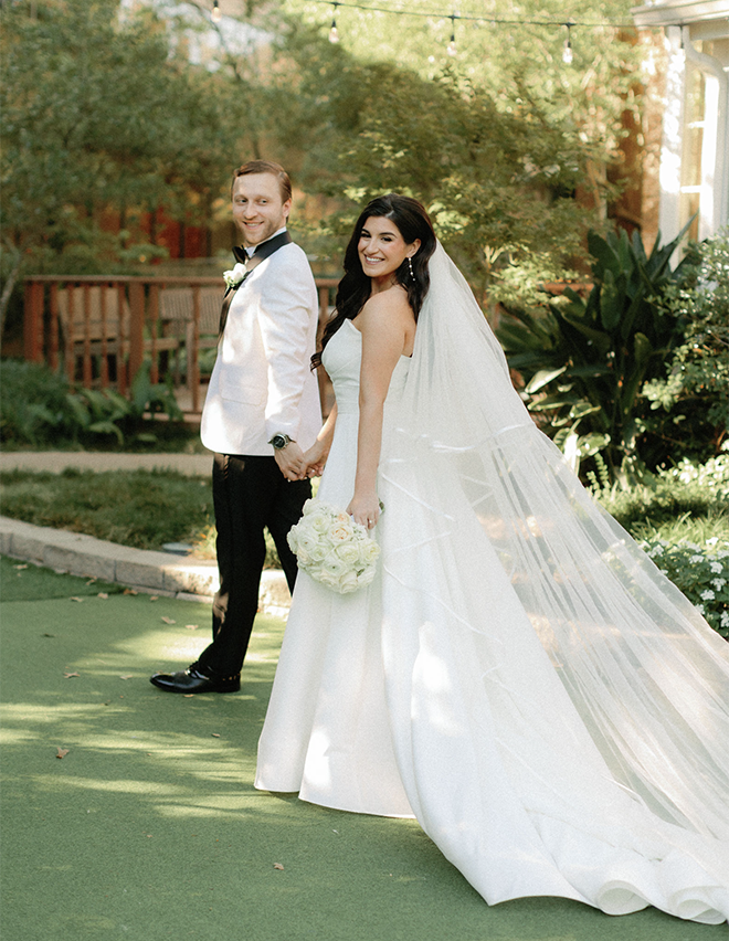 The bride and groom holding hands walking in the lawn of The Houstonian Hotel Club & Spa. 