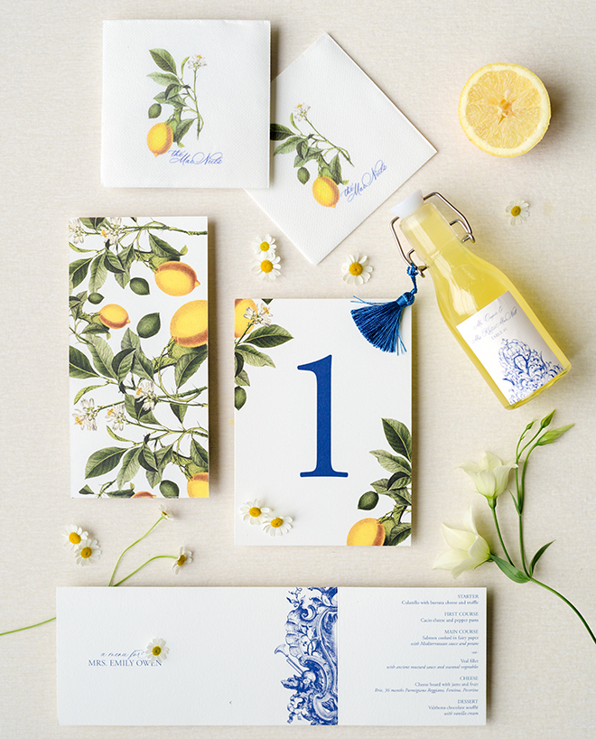 An invitation suite with blue lettering and a lemon print. 