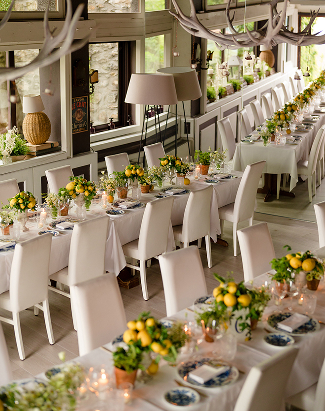 Long white reception tables decorated with lemon centerpieces. 