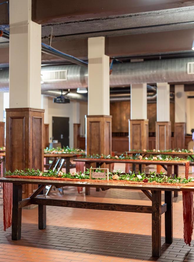 Greenery and terracotta, tan, gold, white & sage green decor and flowers decorate the reception space. 