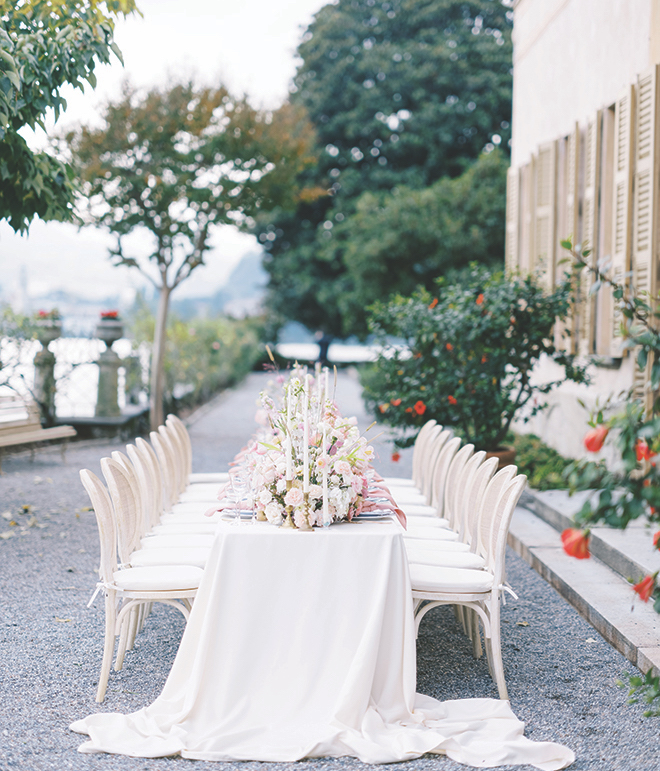 A long white table decorated with florals and candles overlooking Lake Como.