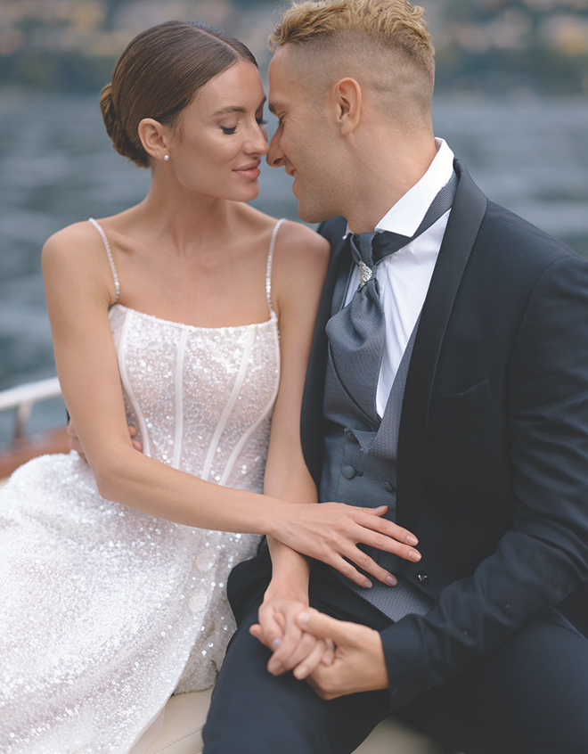 The bride and groom smiling at each other touching noses while sitting on a boat in Lake Como, Italy. 