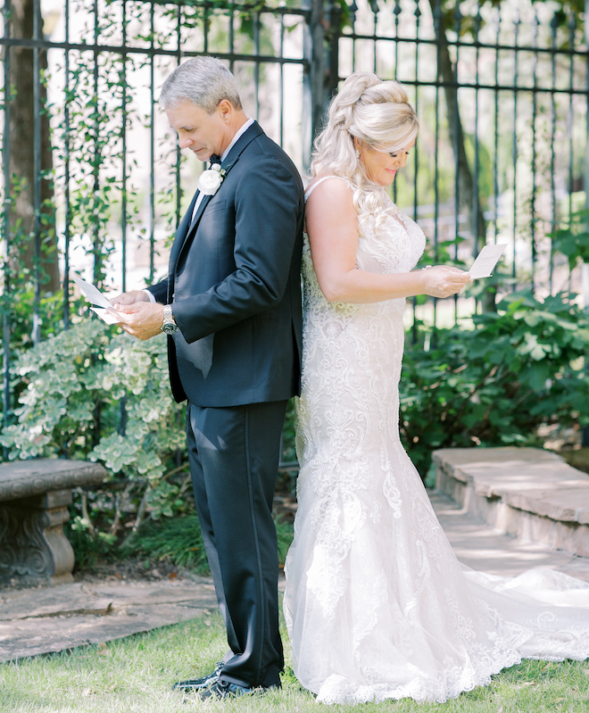 A bride and groom back-to-back reading letters. 