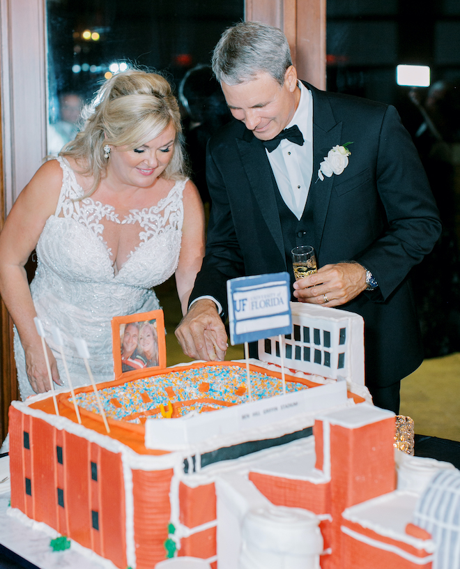 A bride and groom cutting into a groom's cake that is a replica of The University of Florida stadium. 