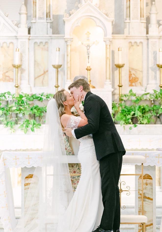 The bride and groom kiss at the alter during their ceremony at a church in Galveston.