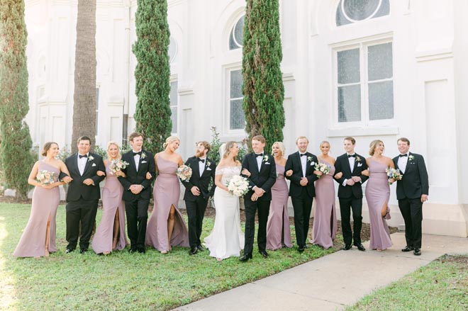 The bride and groom and their wedding party stand outside of a church in Galveston.