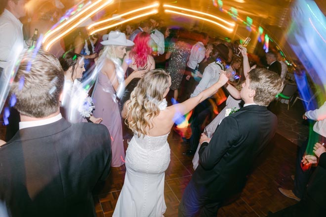 The bride and groom dance with their wedding guests at their light and airy wedding.