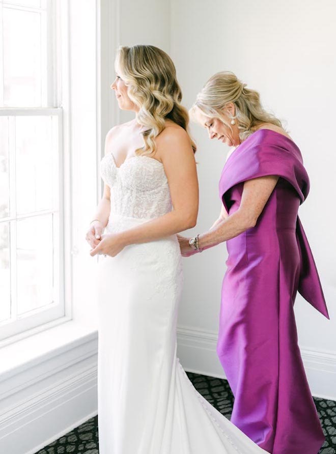 The bride's mother zips her into her wedding gown.