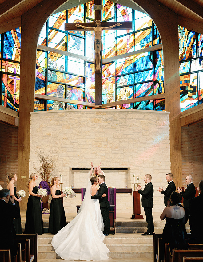 The bride and groom kissing at the altar of a church. 