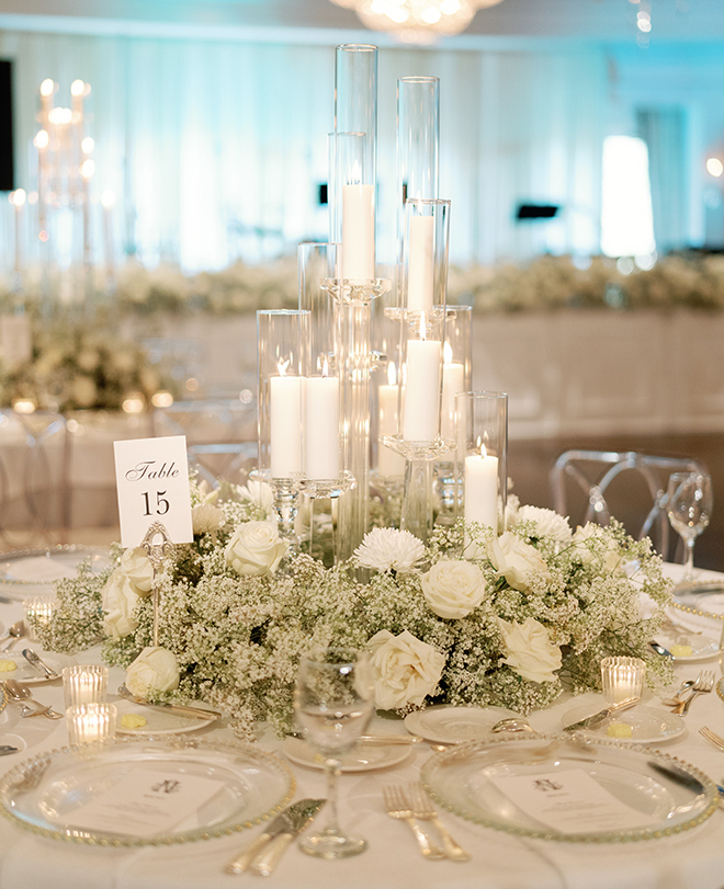  A reception table decorated with white linens. baby's breath and candles.