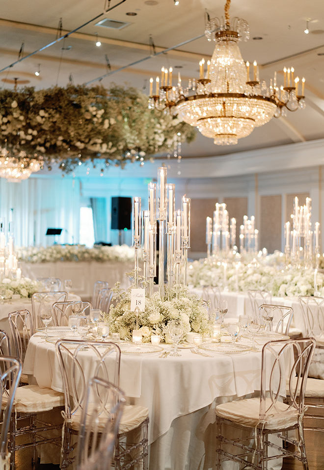 A ballroom decorated with white linens. baby's breath and candles on the reception tables.