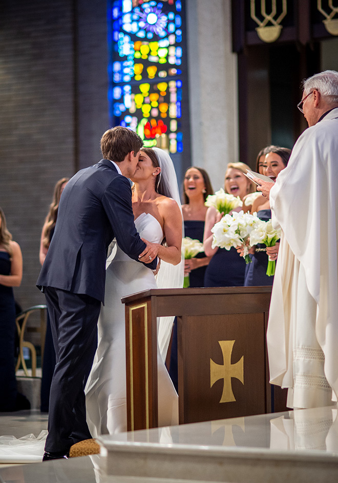 The bride and groom share a kiss at the altar during their wedding ceremony.