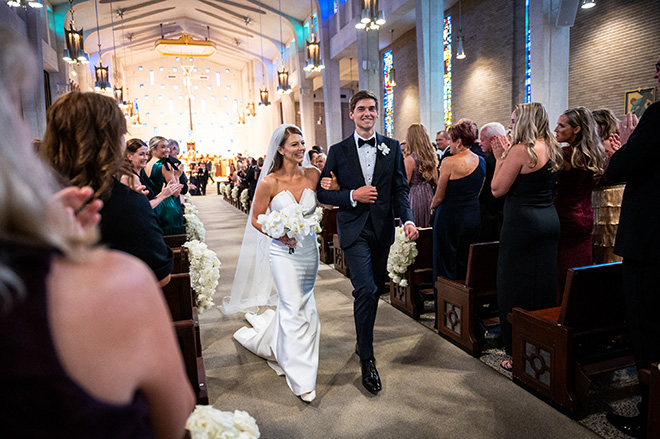 The bride and groom walk down the aisle locking arms after their wedding ceremony.