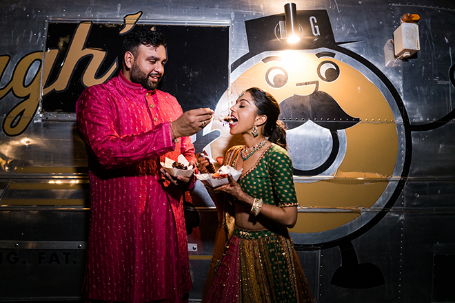 The groom feeding the bride a donut in front of a donut food truck. 