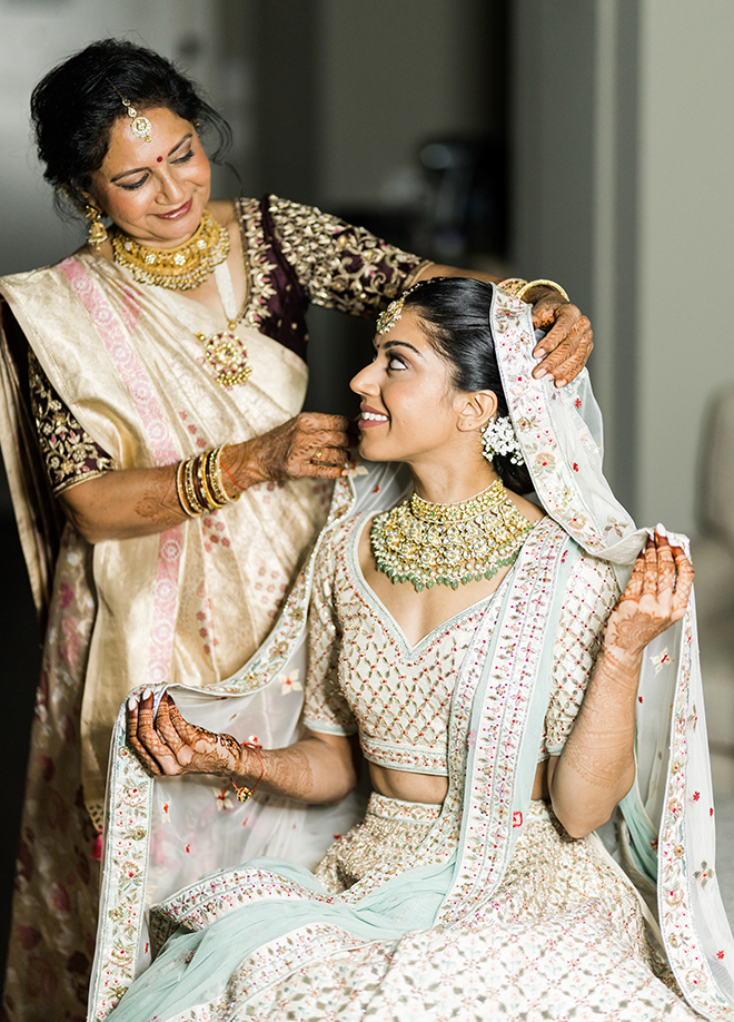 A bride's mother helping her get ready before her wedding ceremony. 