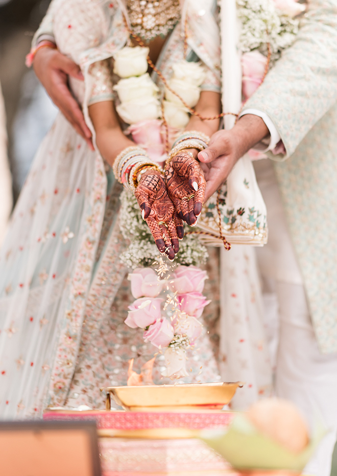 The groom holding the bride's hands covered in henna during a ritual. 