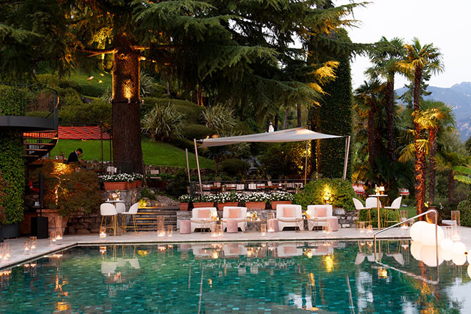 There are lounge chairs with pink pools sitting around the pool at the Grand Hotel Tremezzo.