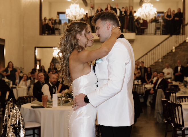 Wedding guests watch as the bride and groom dance on the dance floor.