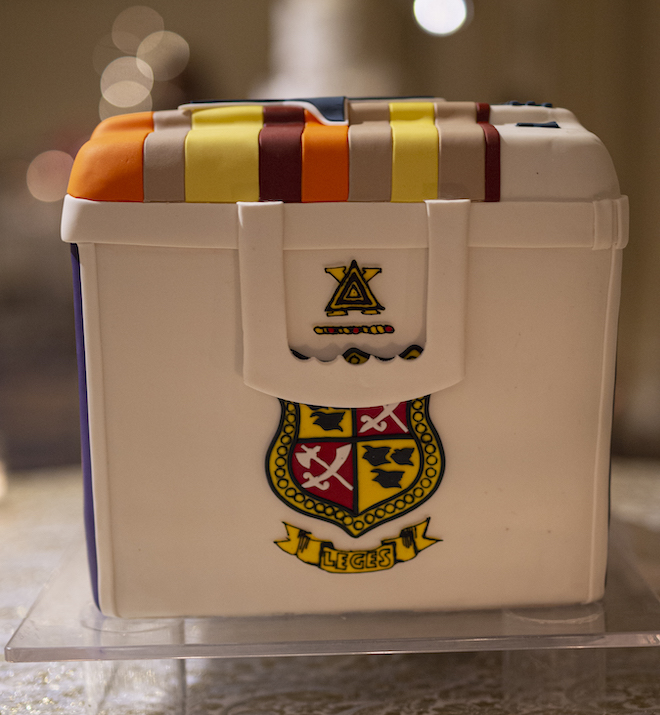 A colorful white cake designed as an ice chest with the word "leges" written across it. 