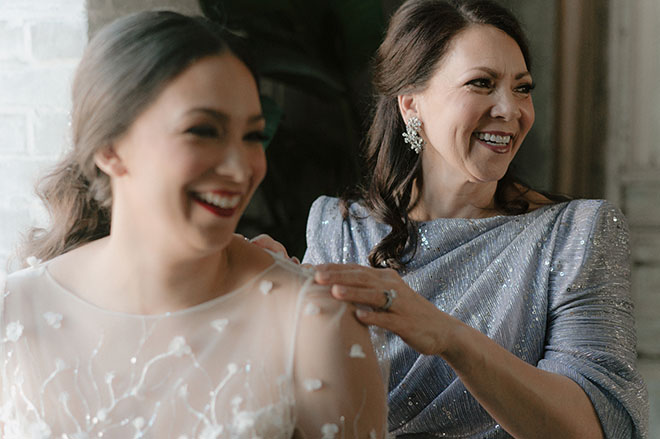 The mother of the bride helps her daughter get into her wedding gown.