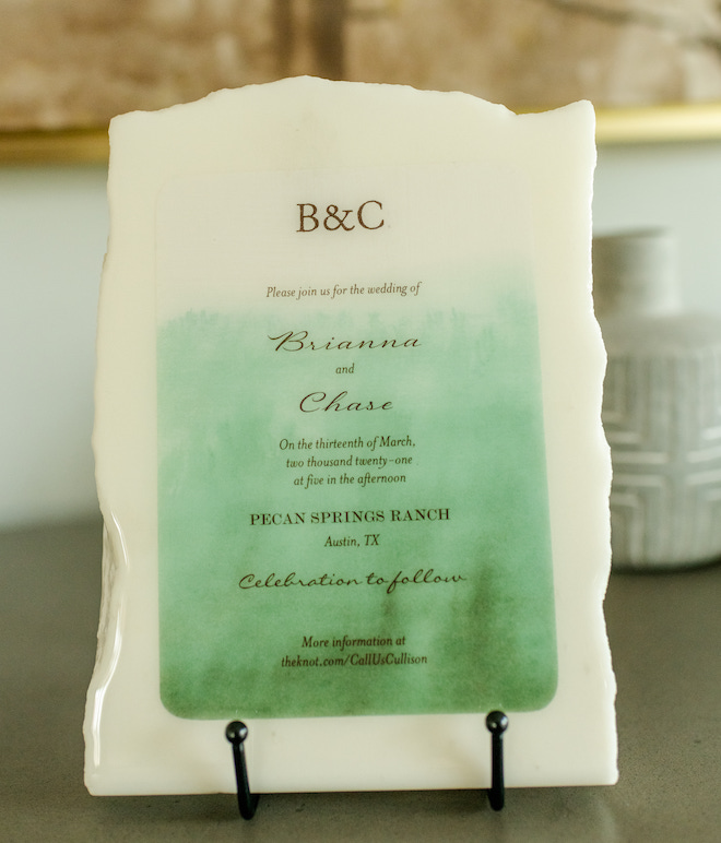 A shiny white piece of marble plaque, with the initials B&C engraved as a wedding invite. With green colors. 