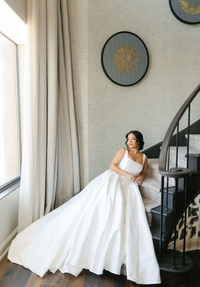 The bride lays on the stairs in the penthouse suite of JW Marriott Houston by The Galleria.