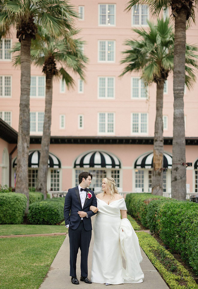 Bride ans groom smiling at each other in front of the Grand Galvez. 