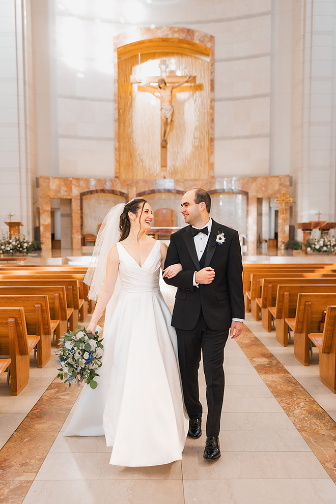 The bride and groom happily leave the church ceremony hand and hand. 