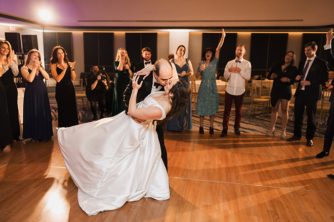 The groom dips the bride during their first dance and kisses her. 