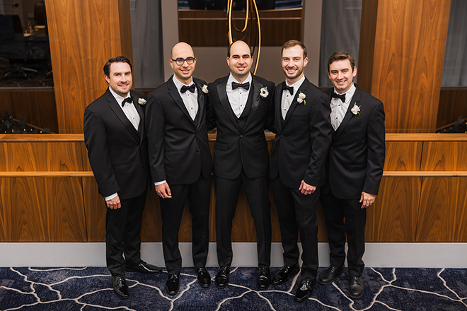 The groom stands with his groomsmen at the church ceremony. 