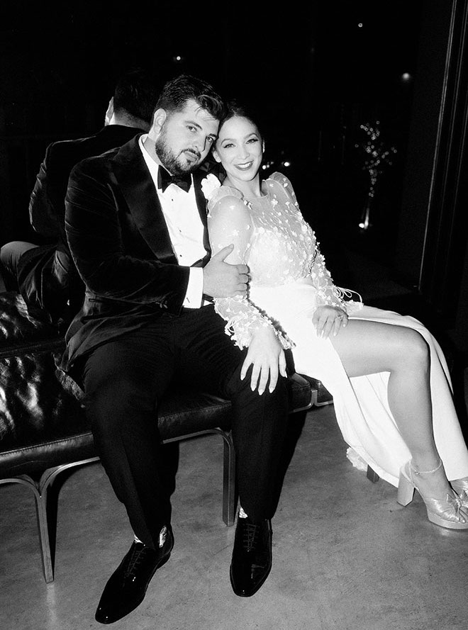 The bride and groom sit on a bench at their champagne and copper wedding at The Astorian.