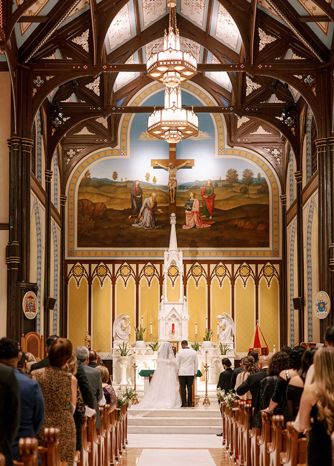 The bride and groom stand at the altar holding hands at their traditional church ceremony.