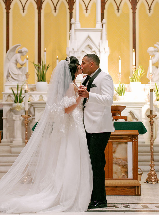 The bride and groom share a kiss at the wedding altar.