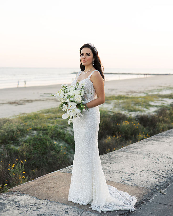 The bride stands along the Galveston seawall in front of The San Luis Resort, Spa and Conference Center.