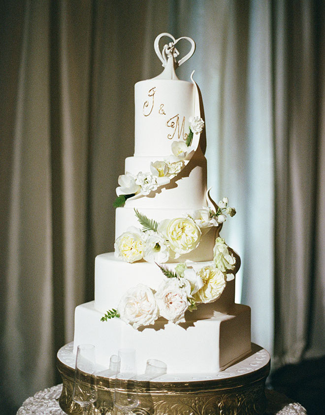 Cakes by Gina designs a five-tier white wedding cake with white roses for the couple's beachside wedding.