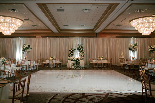 The venue's ballroom is detailed in white flowers, greenery and gold accents for the beachside wedding.