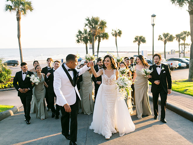 The bride, groom and their wedding party walk up the driveway of the Galveston beachside wedding venue.