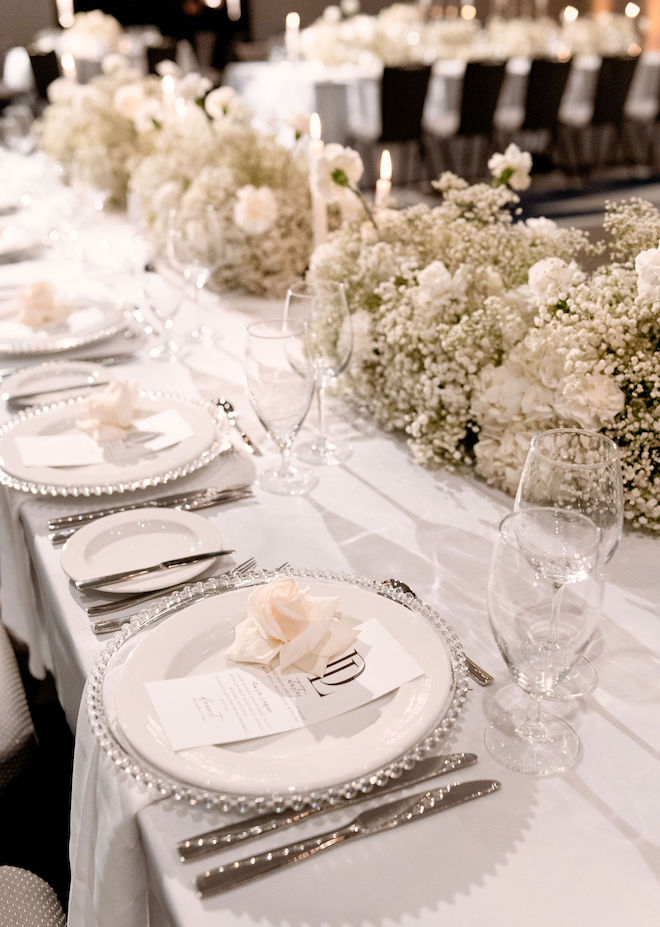 A reception table decorated with white florals and baby's breath. 