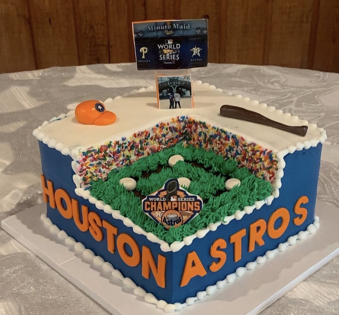 A Houston Astros baseball field designed as a groom's cake with a World Series sign, a baseball hat, and bat. 