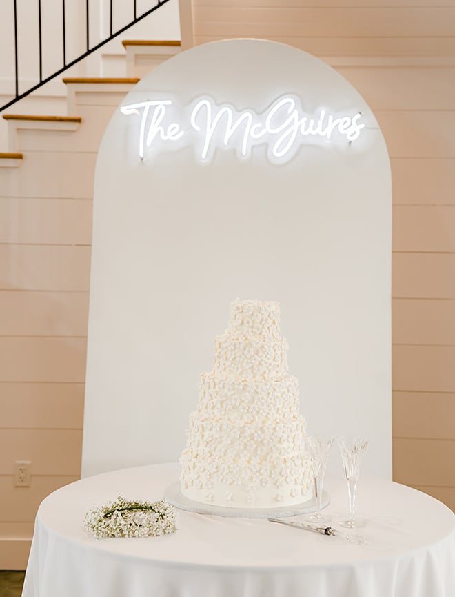 The wedding cake is white with a neon sign hanging above that reads, "The McGuires."