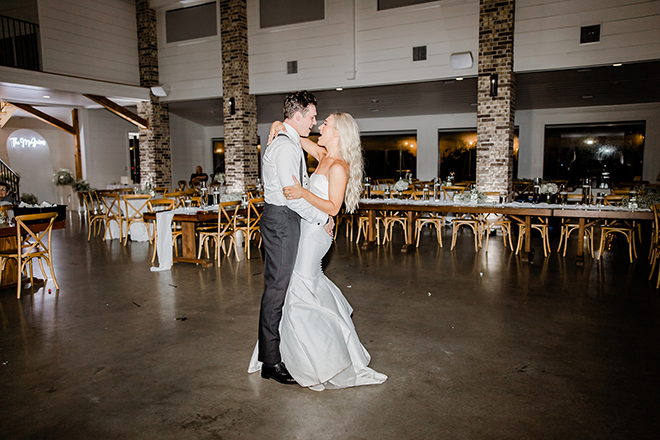 The bride and groom dance at night in the ballroom. 